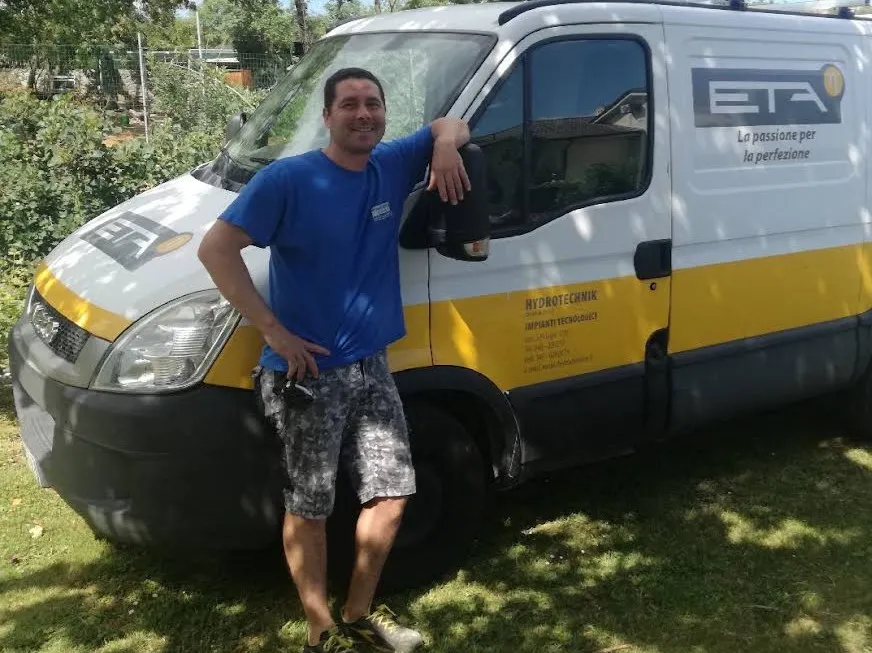 Vanja Devetak accanto al furgone Hydrotechnik, con la livrea che elenca riscaldamento, idrico-sanitari, gas, condizionamento, caldaie a biomassa e sistemi solari